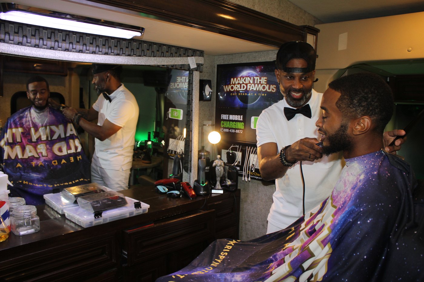 The mobile barbershop in use, with branded capes