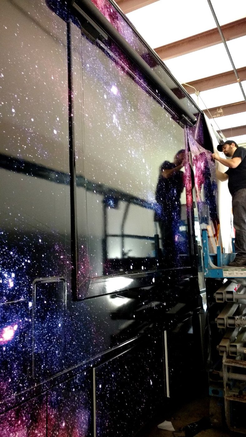 The Makin The World Famous wrap being installed on the RV